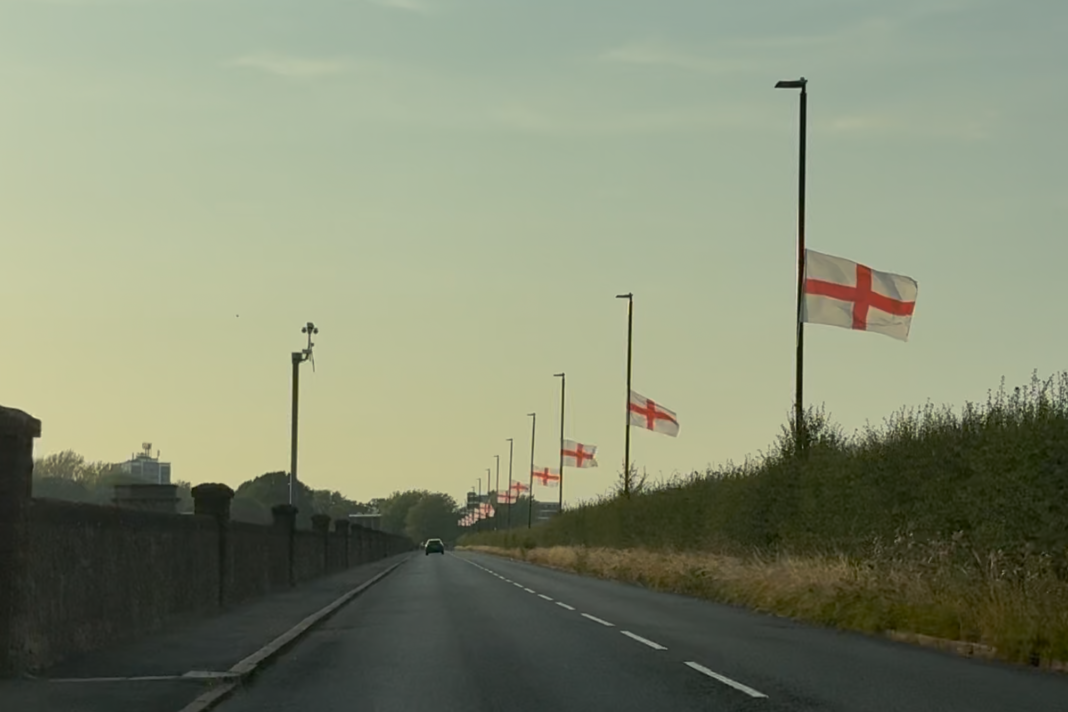 A straight road with England flags tied to lamp posts